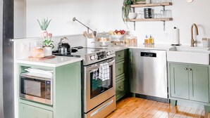 A kitchen with a built-in oven, a sink, and a stove. There is a wooden floor and a ceiling with exposed beams.