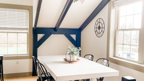 A dining area with a white table, black chairs, and a ceiling with exposed beams.