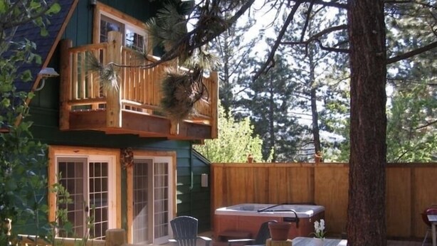 Une cabane à deux étages dotée d’un jacuzzi, de chaises longues et d’une clôture en bois.