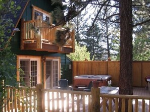 Une cabane à deux étages dotée d’un jacuzzi, de chaises longues et d’une clôture en bois.