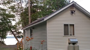 A single-story house with a sloped roof, a small window, and a chimney. -  A Little Piece Of Heaven (Brownville)