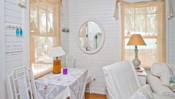 Une pièce confortable avec un lit, une table avec une lampe, une chaise et une fenêtre avec des rideaux.