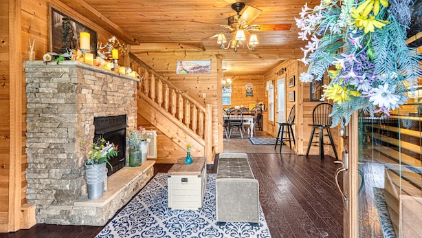 A wooden interior with a stone fireplace, a staircase, and a dining area. - End of Summer Retreat Stunning Views, Horses, Pool (Sevierville)