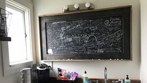 A kitchen with a blackboard listing cities and a coffee maker. - Cut Bank Unit #1 near Glacier National Park! (Cut Bank)