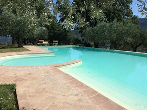 A clear swimming pool with a tiled deck, surrounded by trees and a view of a mountainous landscape. - Old Country House and pool In Umbrian Hills Between Foligno And Assisi (Foligno)