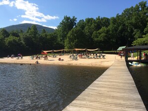A beach with a wooden pier extending into calm water, surrounded by lush green trees and a clear sky. - Recent improvements, walk to events, trails and slopes (Wintergreen)