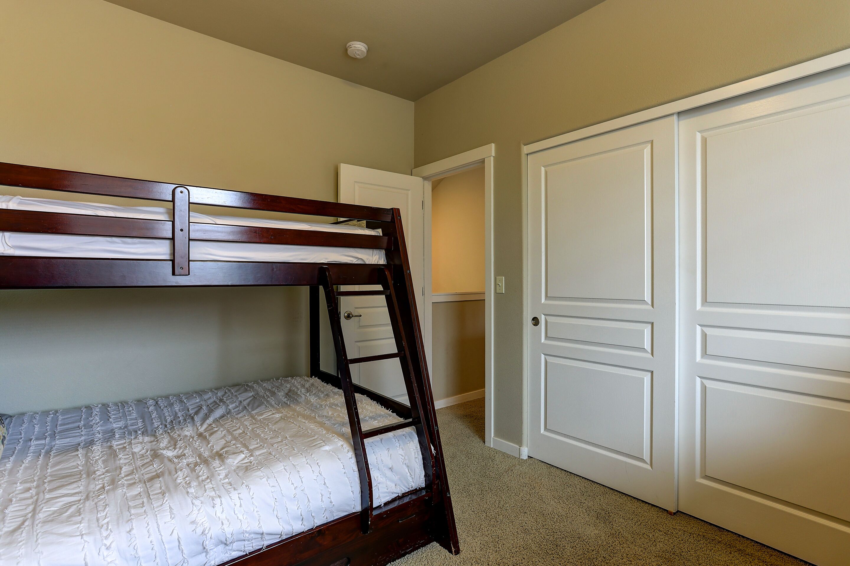 A bedroom with a bunk bed, a door, and a closet.