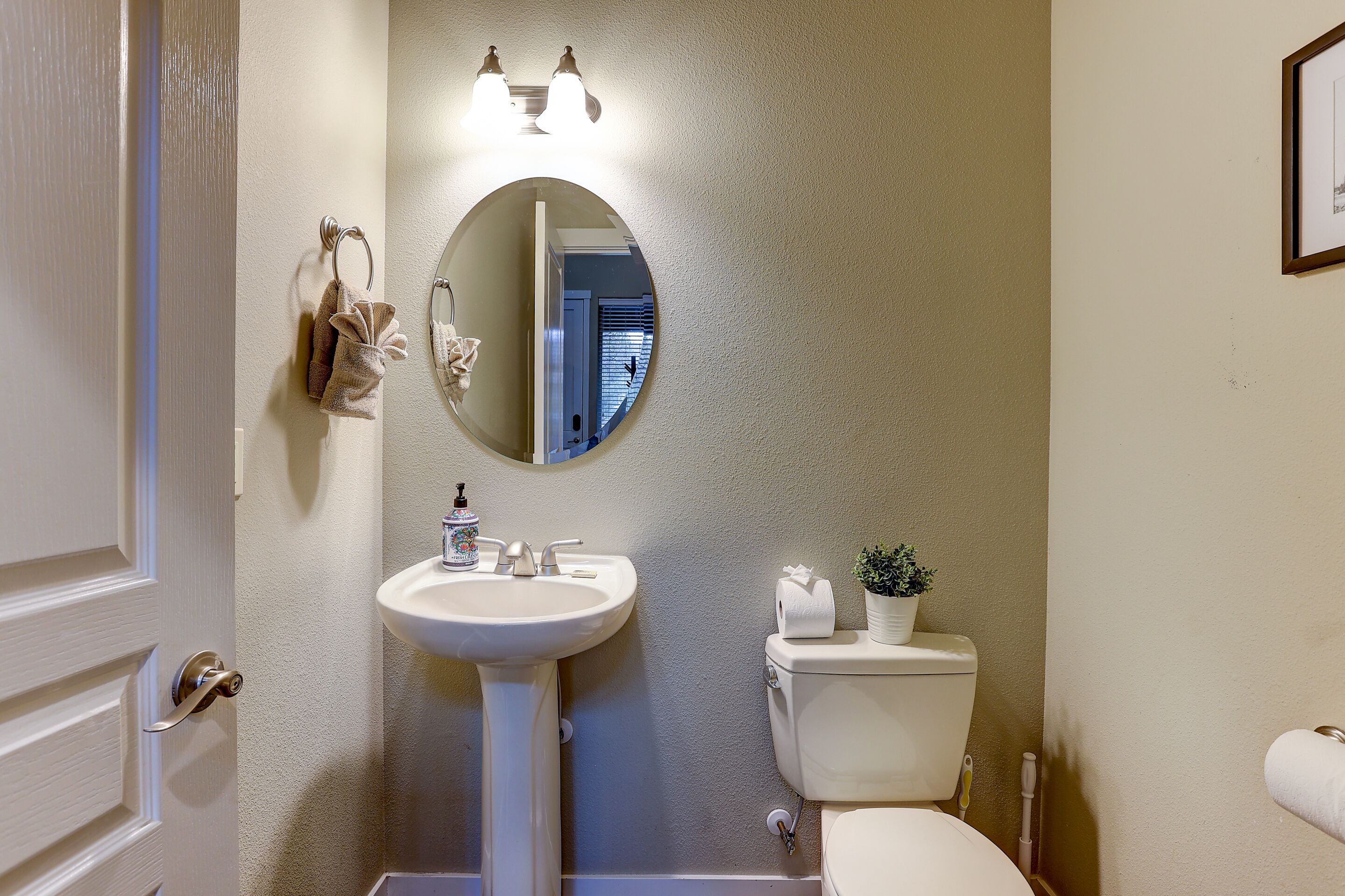 Une salle de bain avec un lavabo blanc, des toilettes, un miroir et un porte-serviettes.