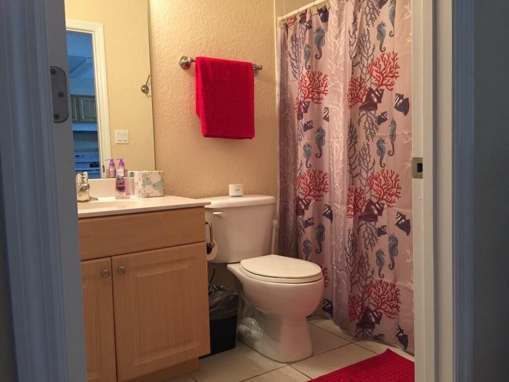 Une salle de bain équipée de toilettes, d’un lavabo et d’un rideau de douche orné de motifs représentant la vie marine.