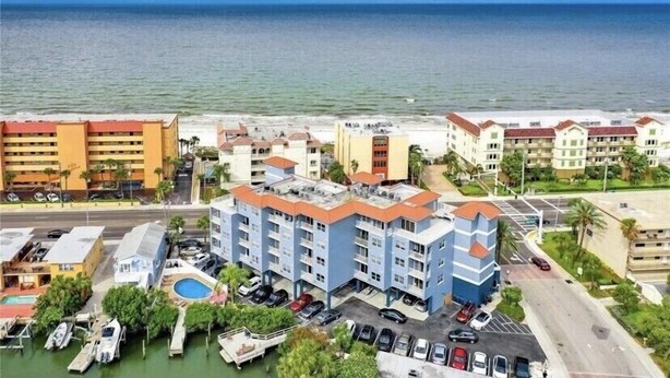 A coastal hotel with multiple buildings, a marina with boats, and a beach in the background. - Beautiful water views at the Skyline Resort (Madeira Beach)