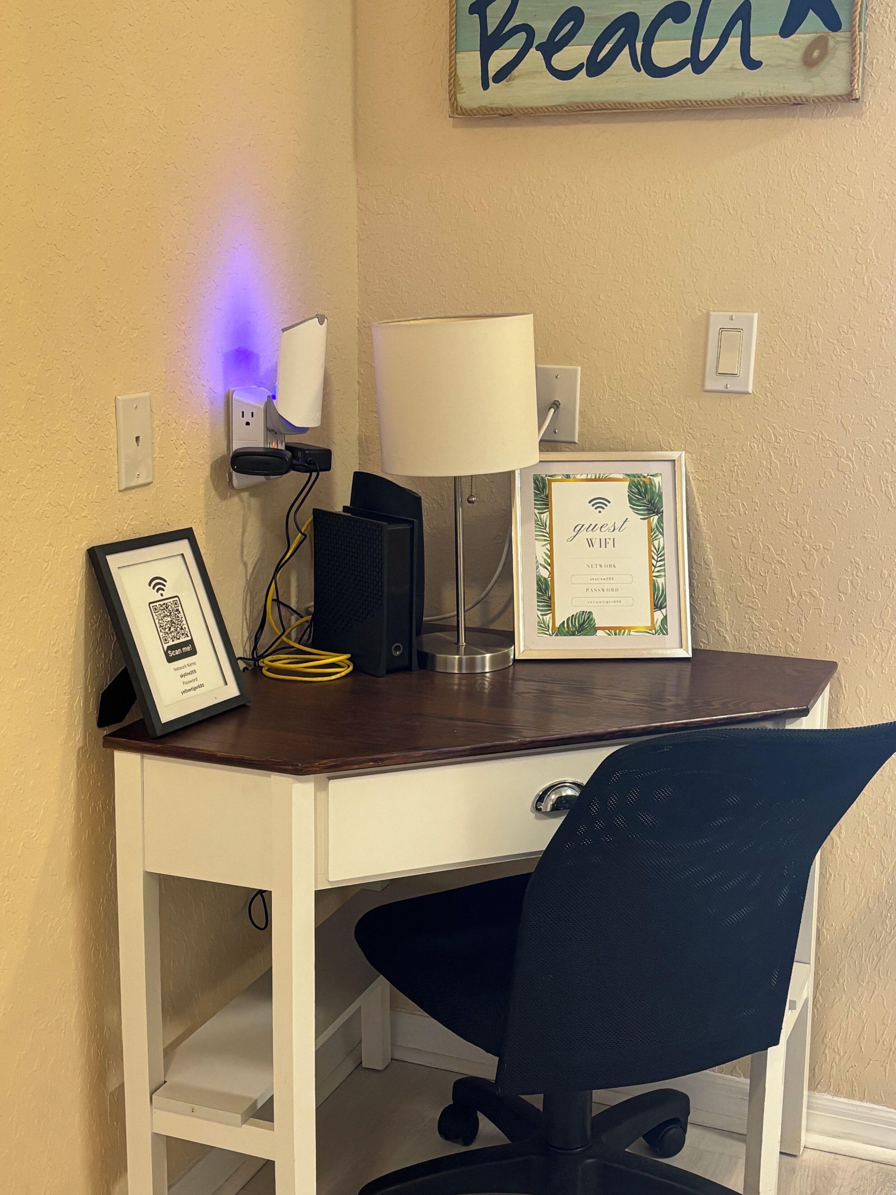 A desk with a lamp, framed artwork, and a QR code.