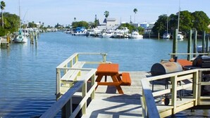 A marina with docked boats, a wooden pier with benches, and a clear view of the water. - Beautiful water views at the Skyline Resort (Madeira Beach)