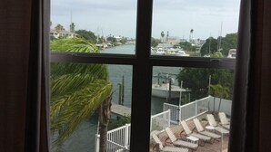 A view from a window overlooking a marina with boats, a dock, and a palm tree. - Beautiful water views at the Skyline Resort (Madeira Beach)