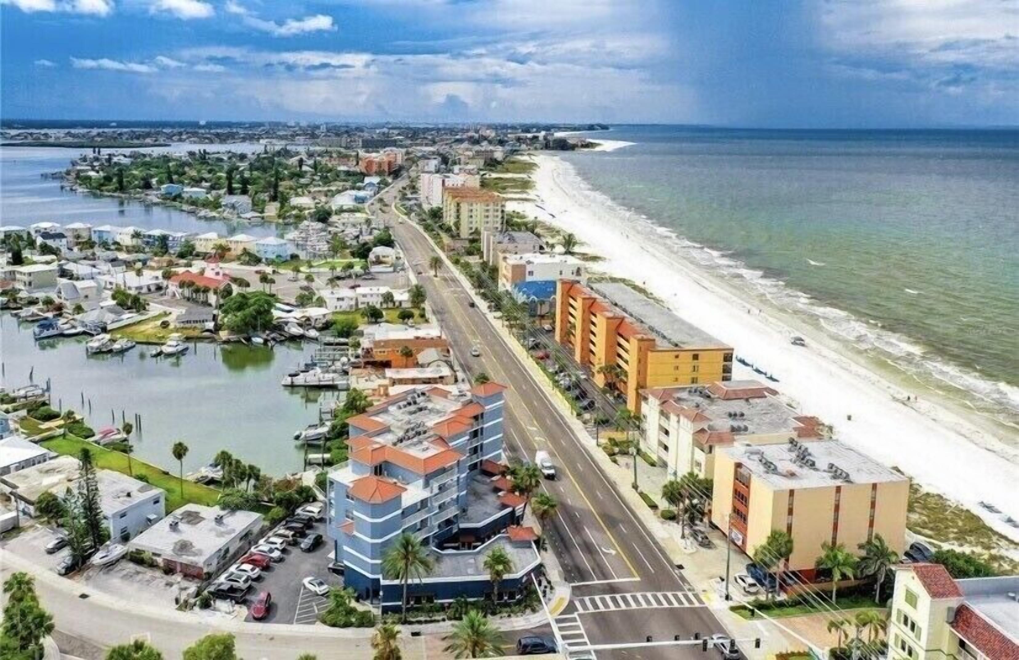 A coastal cityscape with a marina, beachfront hotels, and a road leading to the beach.