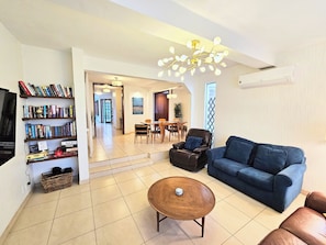 A living room with a sofa, coffee table, bookshelf, and dining area. - Rooftop Ocean views, great outdoor space,  A/C,  prime location, gated, firepit (Ensenada)