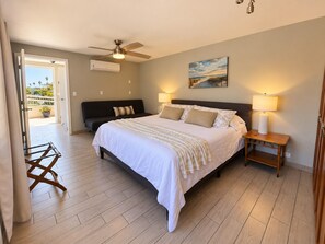 A bedroom with a bed, bedside lamps, a ceiling fan, and a painting on the wall.