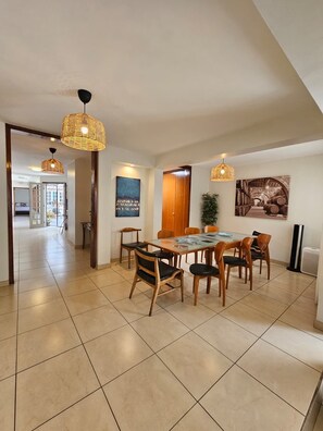 A dining area with a glass table, wooden chairs, and woven pendant lights.