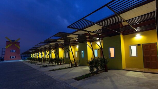 A row of yellow buildings with a windmill in the background. - The Moonlight Resort (Ban Chang)