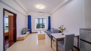 A modern living room with a sofa, coffee table, TV, and a dining area with a table and chairs. - Pazhou Angda International Aparthotel Canton Fair Branch (Guangzhou)