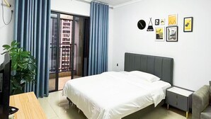 A modern hotel room with a bed, a desk, a chair, a nightstand, a potted plant, and a balcony with curtains. - Pazhou Angda International Aparthotel Canton Fair Branch (Guangzhou)