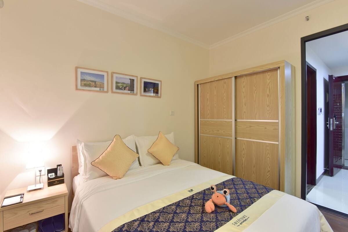 A hotel room with a bed, a nightstand, a wardrobe, and three framed pictures on the wall.
