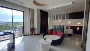 Una sala de estar moderna con un ventanal grande, un sofá redondo negro y rojo, una mesa de centro blanca y un separador de vidrio.