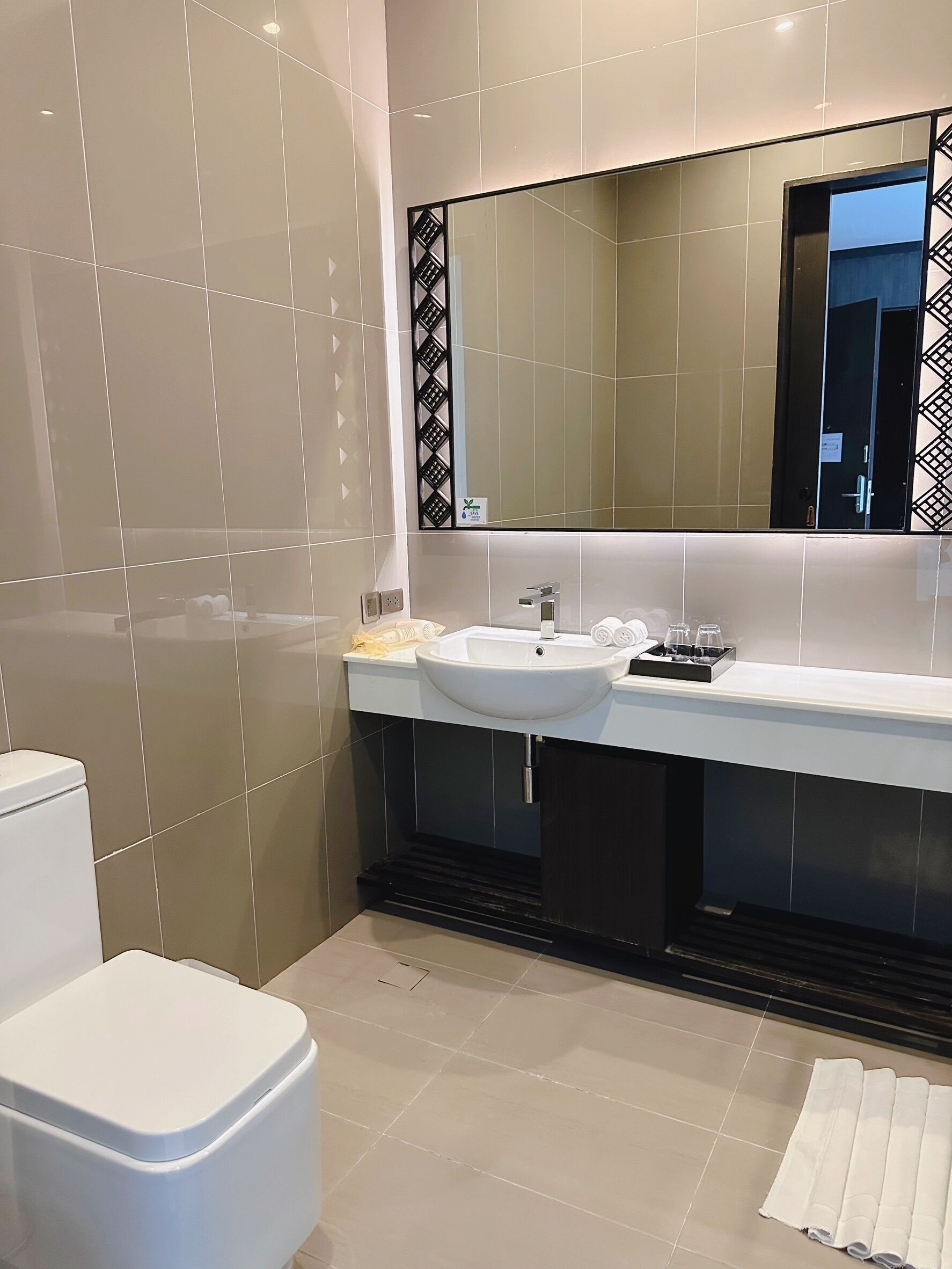 Un baño moderno con un lavamanos blanco, un espejo grande y un inodoro.