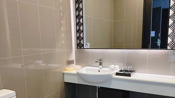 Un baño moderno con un lavamanos blanco, un espejo grande y un inodoro.