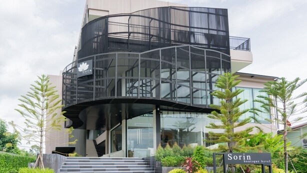 Un hotel boutique con un diseño arquitectónico moderno y curvo, que presenta una escalera destacada que conduce a la entrada.