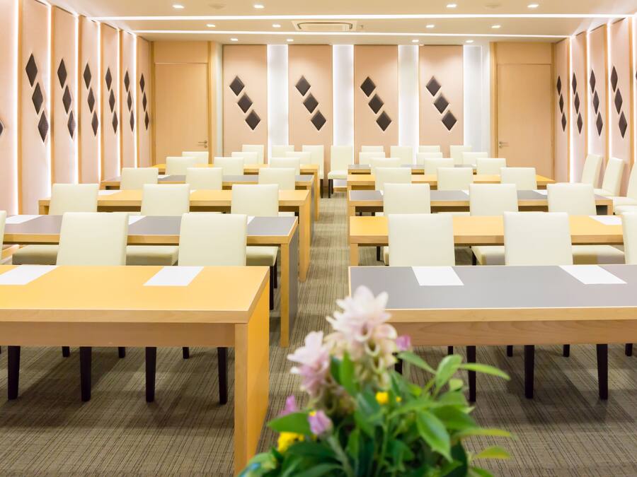 A conference room with multiple tables and chairs, arranged in rows.