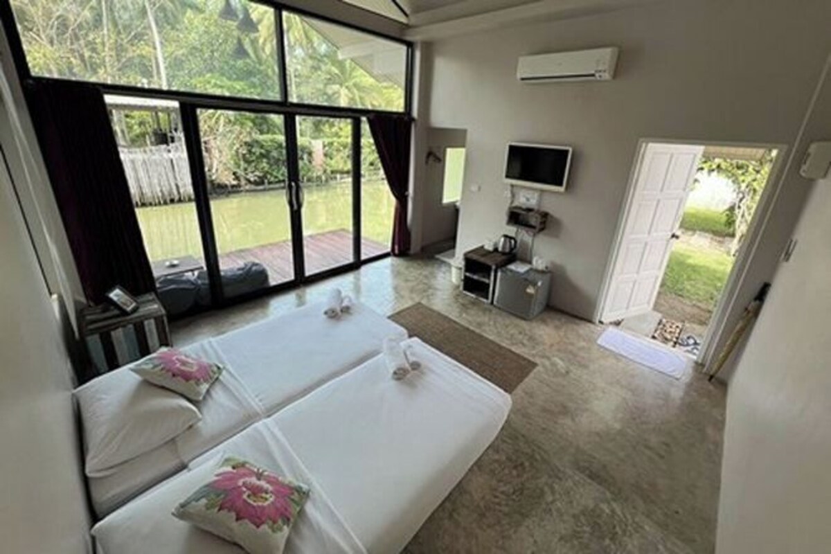 A hotel room with two beds, a TV, a desk, and a sliding glass door leading to a balcony.