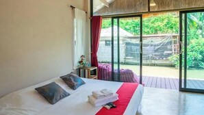 Habitación de hotel con cama, una mesita de noche con lámpara y vistas al exterior a través de amplias ventanas.