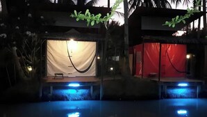 Zona de piscina con una carpa y una estructura roja, rodeada de vegetación.