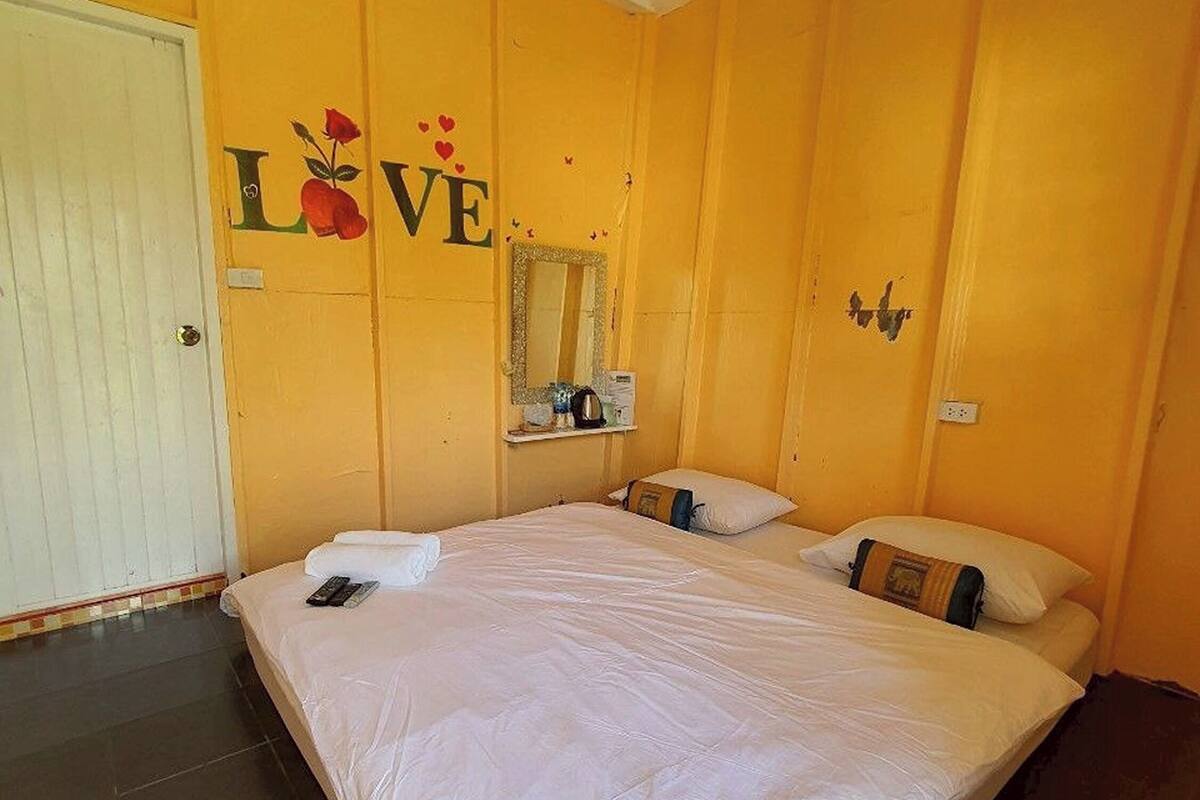 A bedroom with a large bed, a mirror, and a wall decoration with the word "LOVE" and a rose.