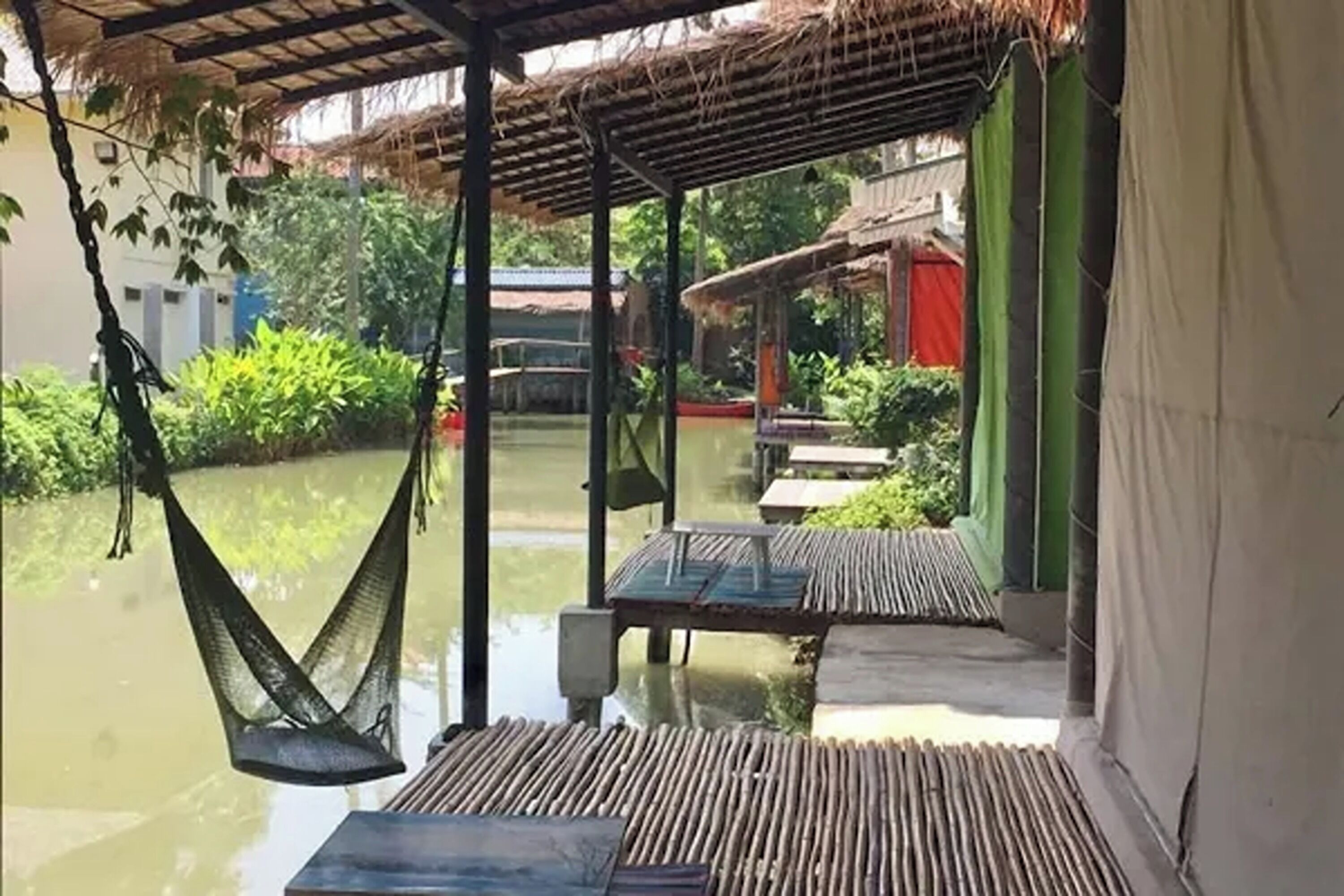 A covered outdoor area with a hammock, tables, and a view of a water body.