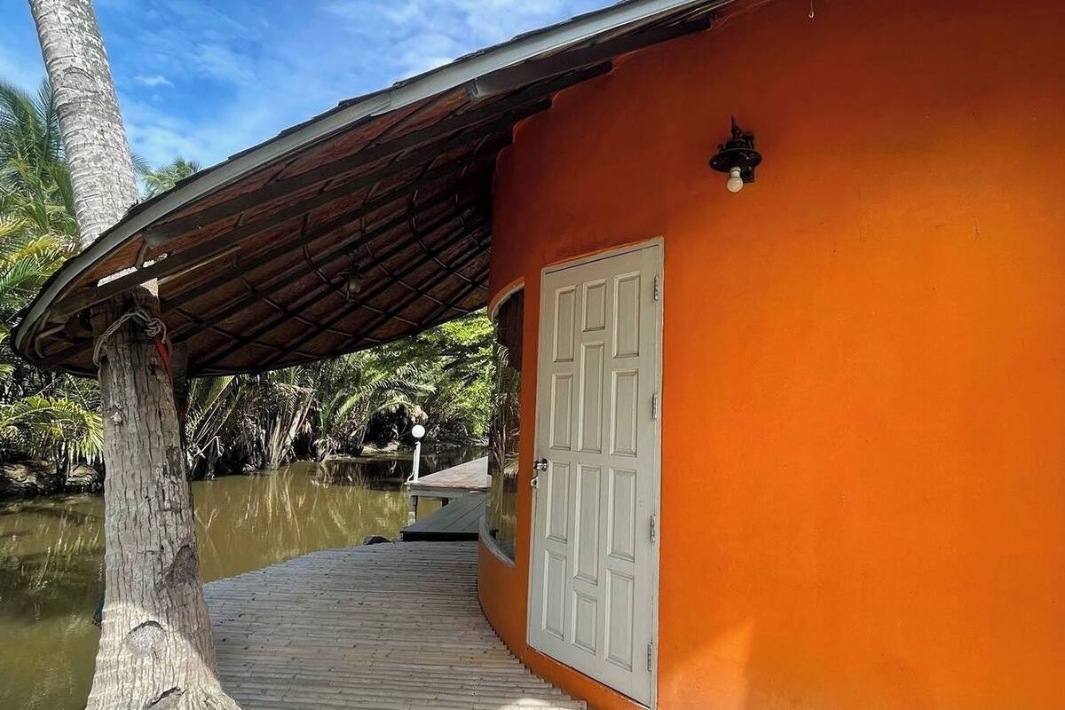 A wooden deck leading to a building with an orange exterior and a white door.