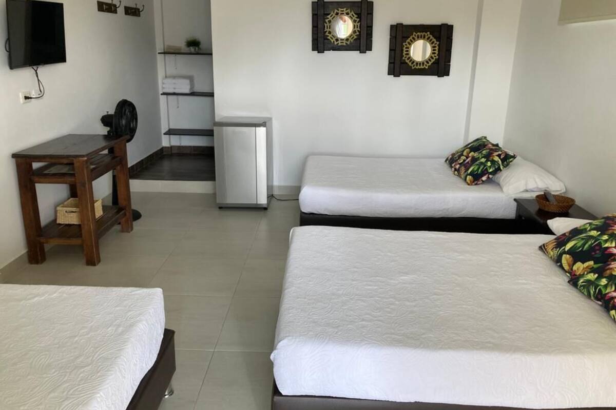 A hotel room with two single beds, a desk with a chair, a television, and two decorative mirrors.