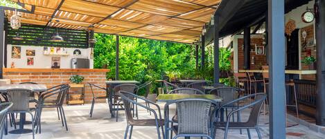 Une terrasse extérieure avec des meubles en osier, un comptoir en briques et un plafond en bois.