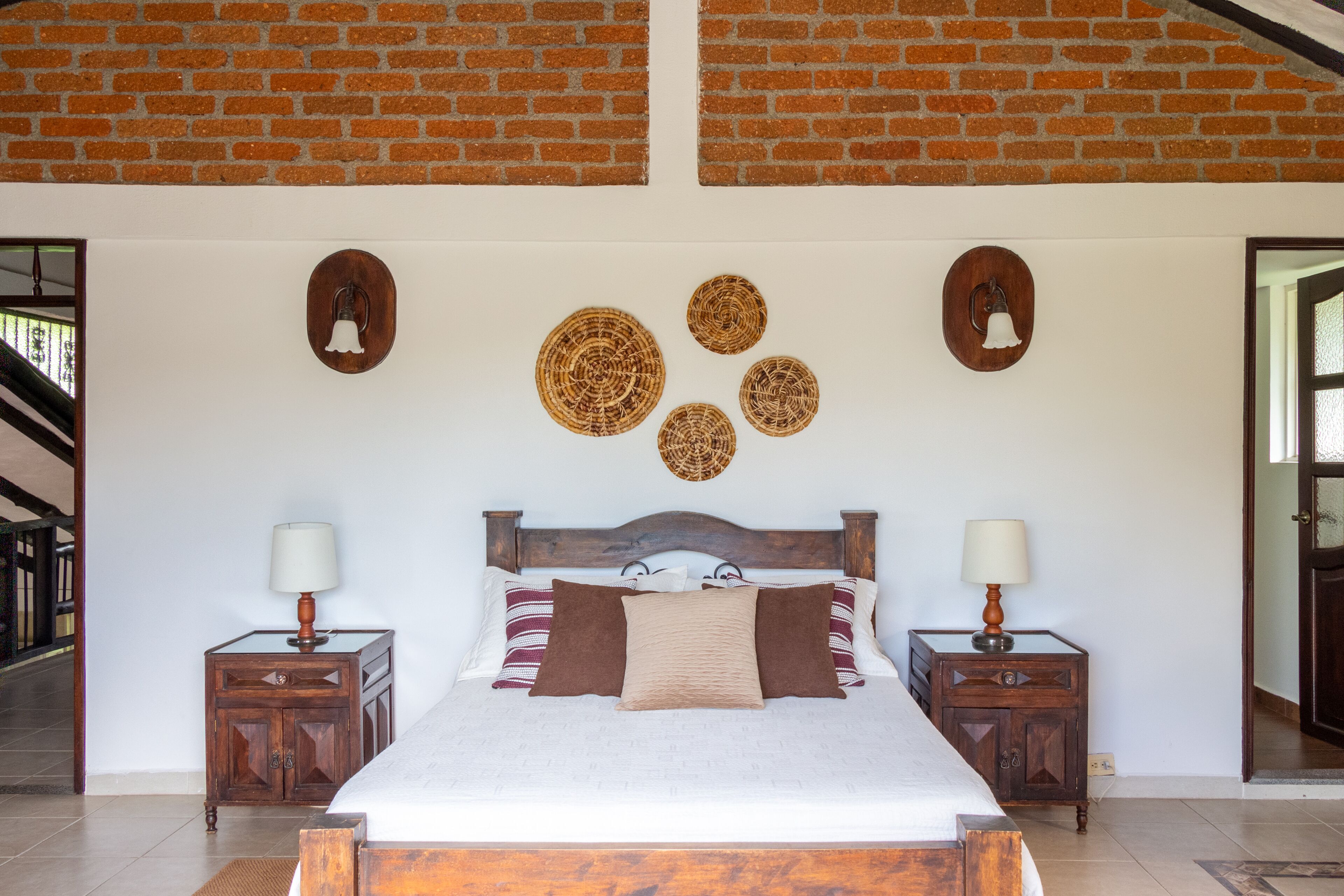 Un dormitorio con techo de ladrillo, una cama grande, dos mesitas de noche y decoración en la pared.