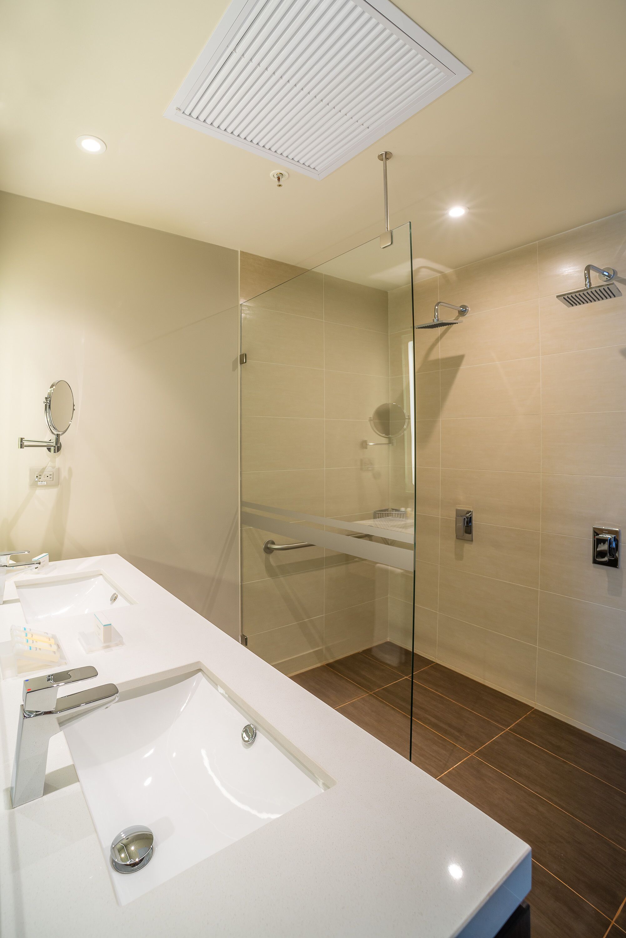 Un baño moderno con ducha envuelta en vidrio, un lavamanos grande de color blanco y un espejo.