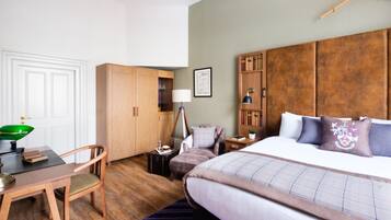 Habitación de hotel con cama, escritorio con silla, armario de madera y estantería.