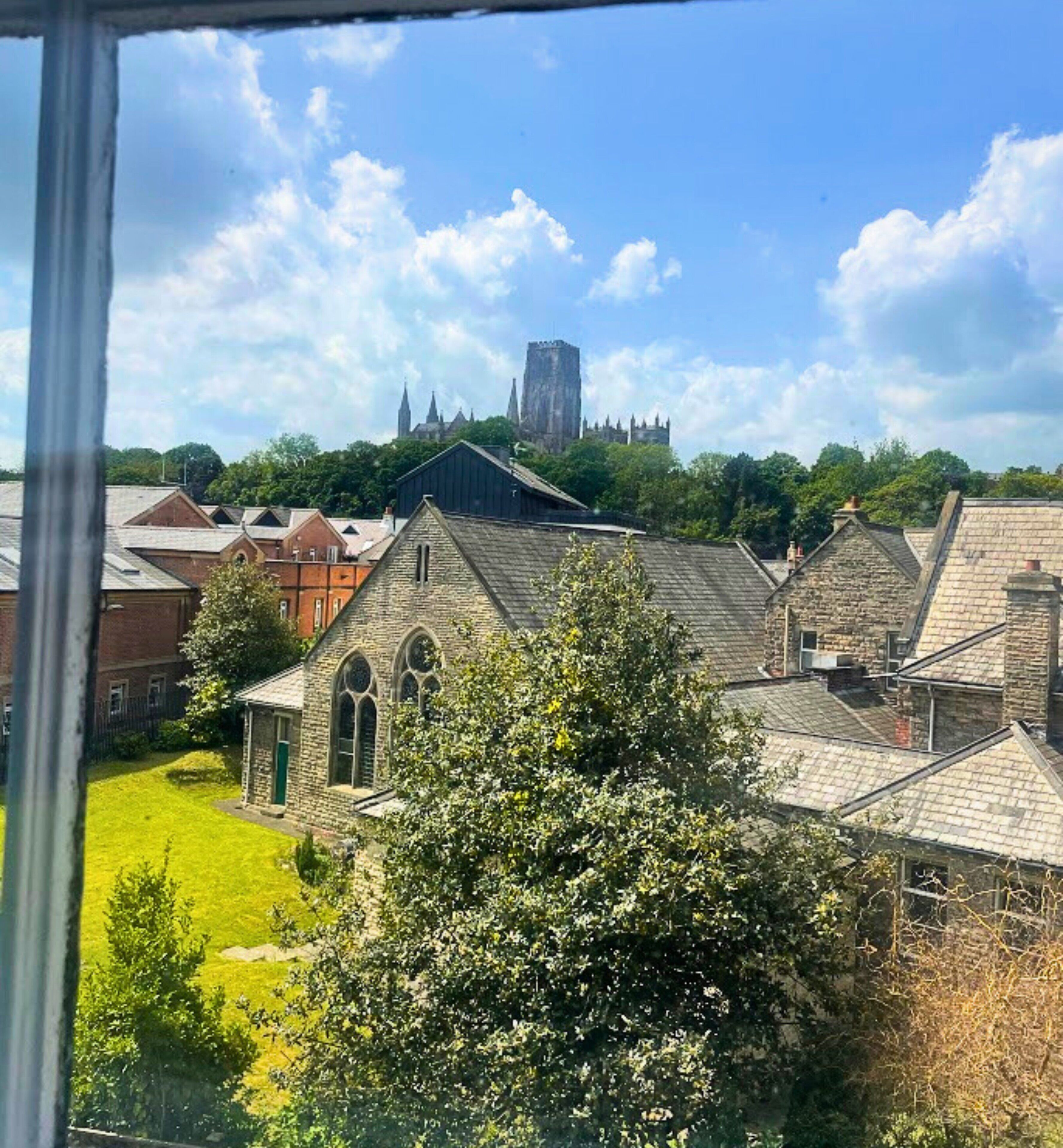 Vista de una iglesia con una aguja alta y un edificio moderno al fondo.
