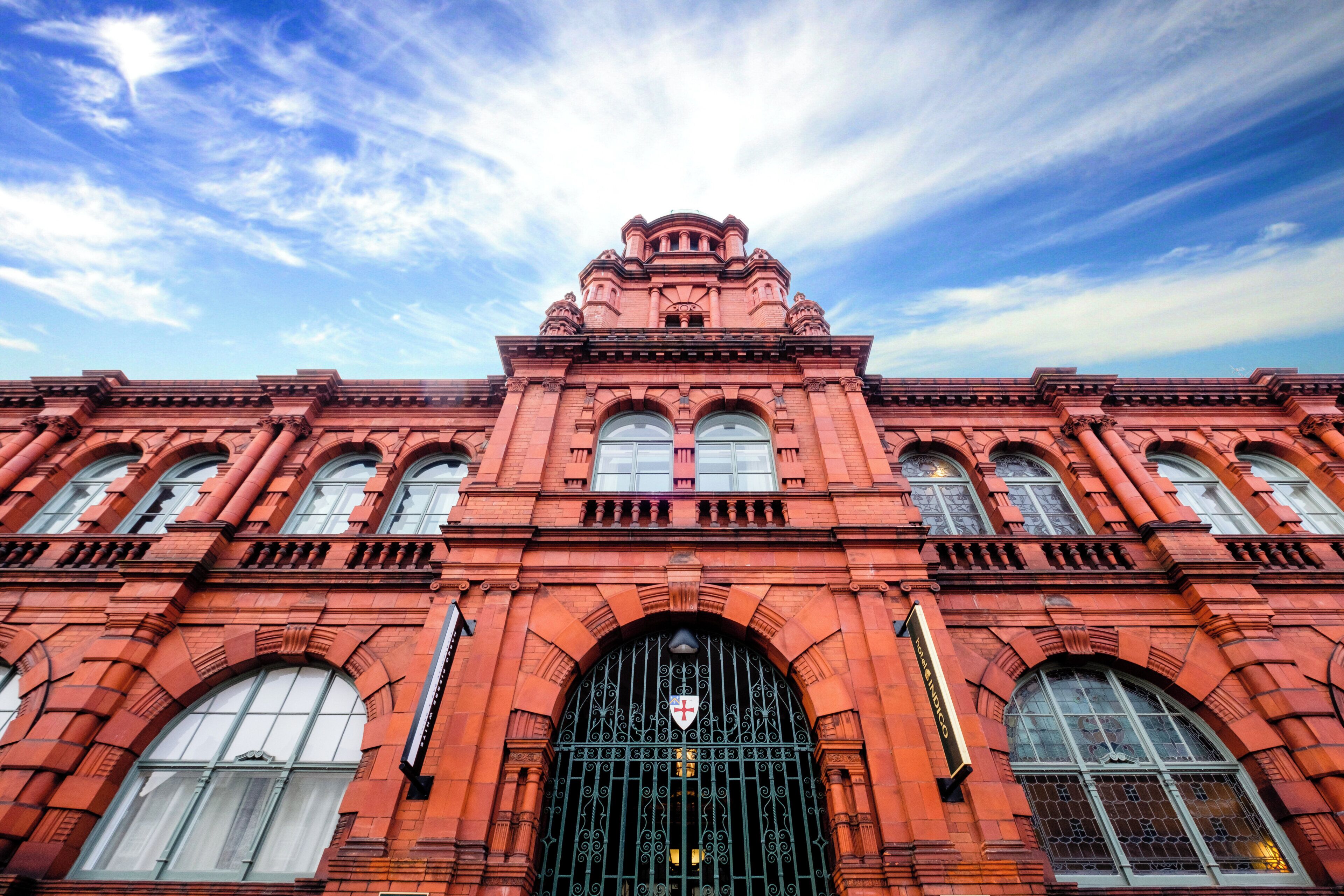 Un edificio de ladrillo rojo con una entrada arqueada grande y varias ventanas.