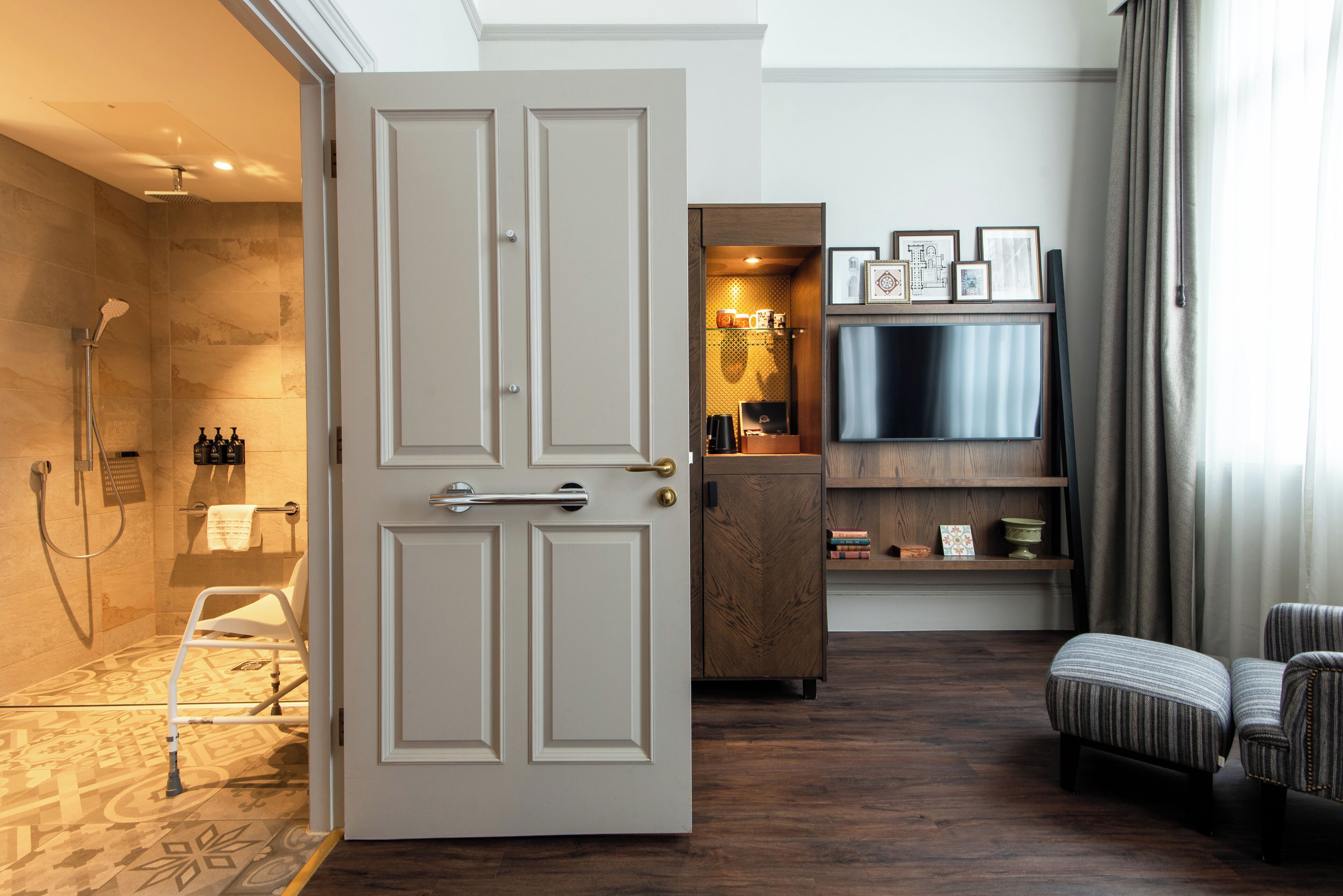 Habitación de hotel con ducha, puerta, televisor, sofá y armario.