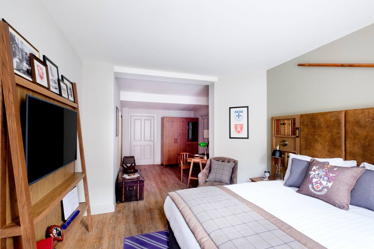 Une chambre d’hôtel avec un grand lit, un bureau, une chaise, une télévision et une bibliothèque.