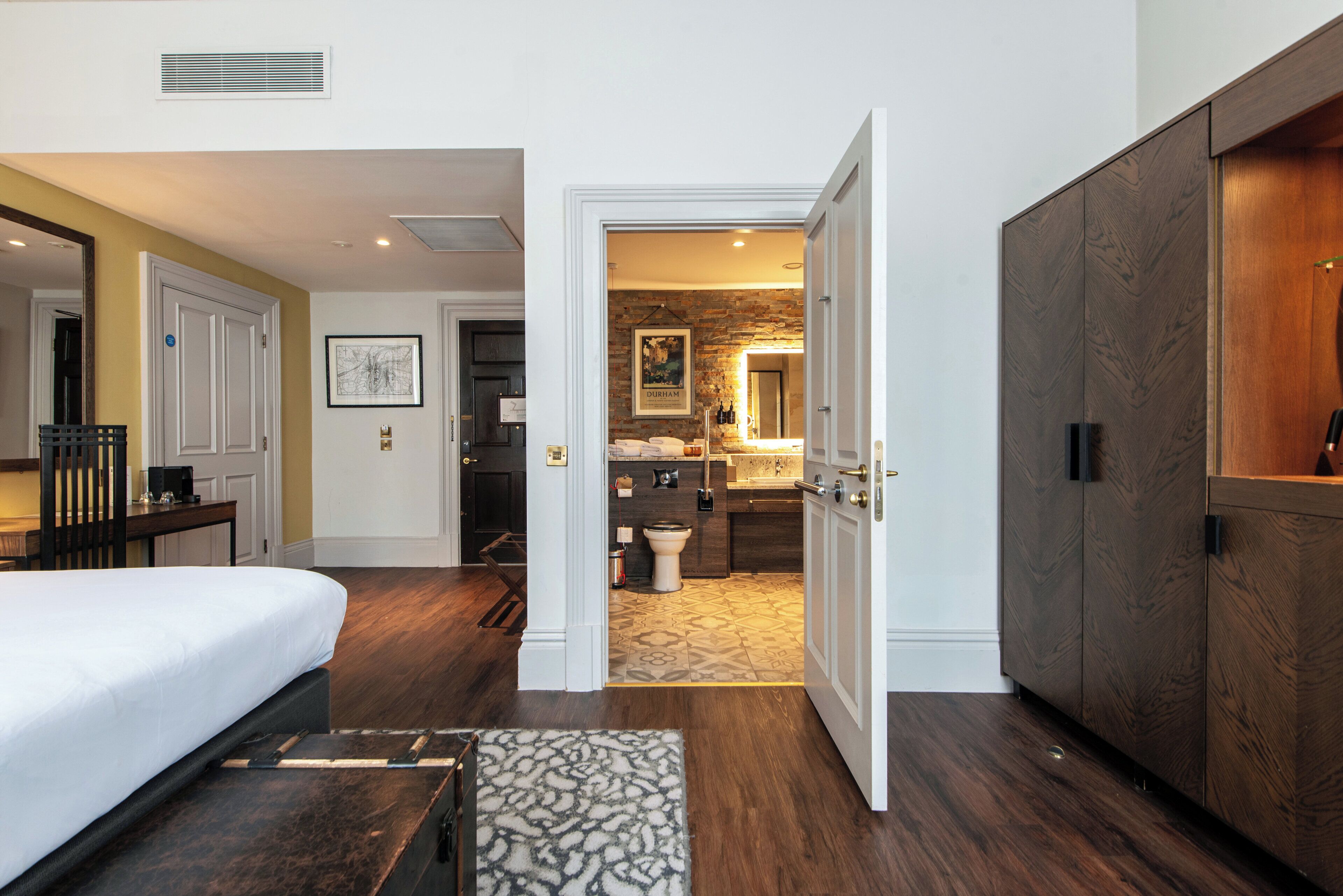 A hotel room with a bed, a desk, a bathroom with a shower, and a wardrobe.