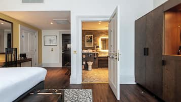A hotel room with a bed, a desk, a bathroom with a shower, and a wardrobe.