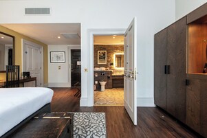 Une chambre d’hôtel comprenant un lit, un bureau, une salle de bain avec douche et une armoire.