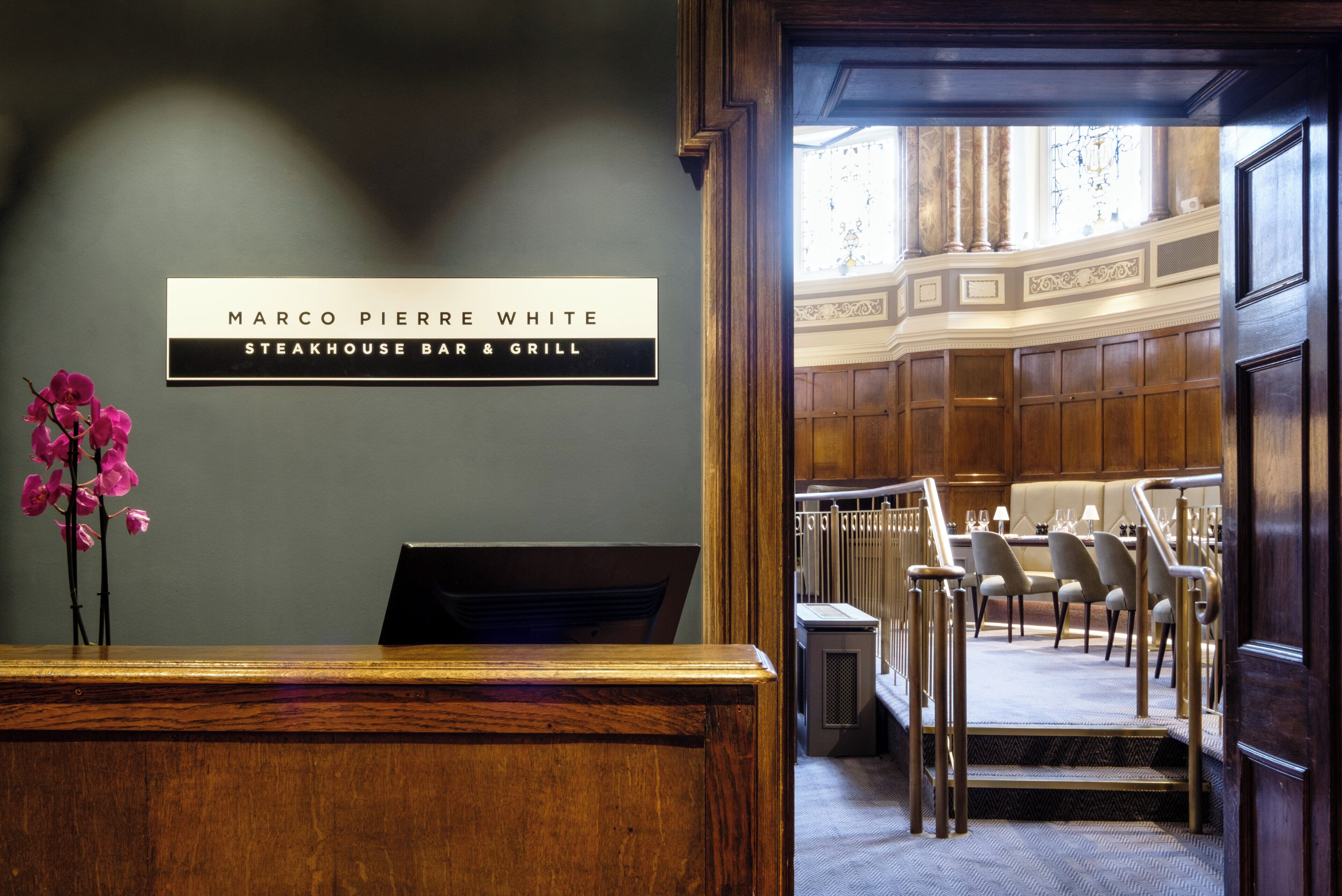 A reception desk with a sign for Marco Pierre White Steakhouse Bar & Grill.