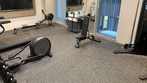 A gym with exercise equipment, a water dispenser, and a view of the outside through a window.